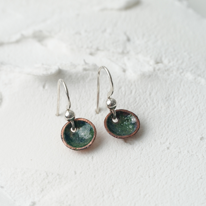 A pair of earrings that are circular and green on silver hooks