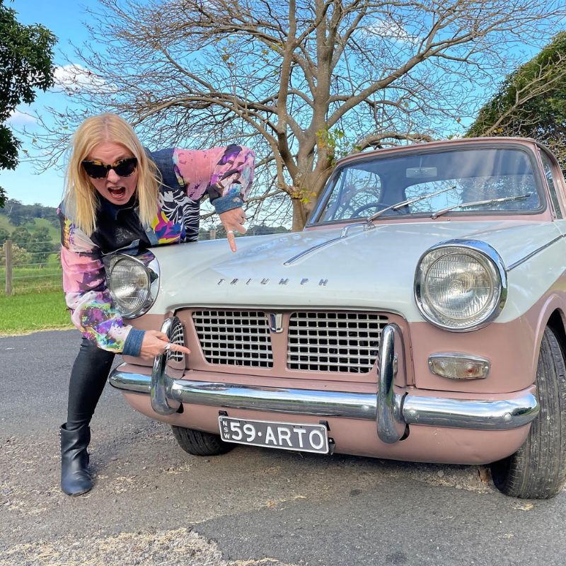 Artomobile Ambassador Photo of Fiona standing in front of a vintage pink car