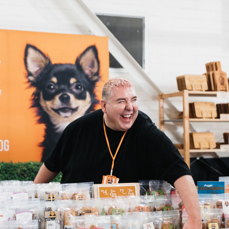 Ryan standing at his colourful pet food stall smiling